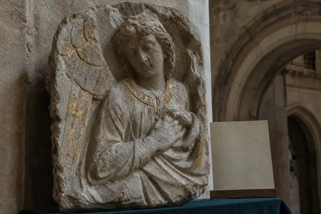 Historisches steinernes Engelrelief mit erhaltenen Spuren einer alten Vergoldung in einem europäischen Kirchenraum.