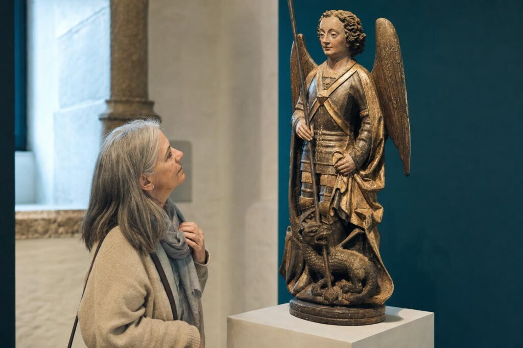 Ältere Frau betrachtet in einem Museum eine historische Darstellung Michaels mit Rüstung und Drachenmotiv.