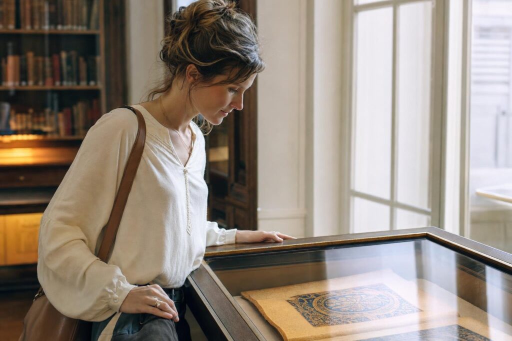 Junge Frau betrachtet in einer ruhigen Ausstellung die Reproduktion einer historischen Handschrift